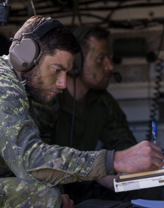 Canadian Armed Forces members monitor radio communications in the back of a Light Armoured Vehicle