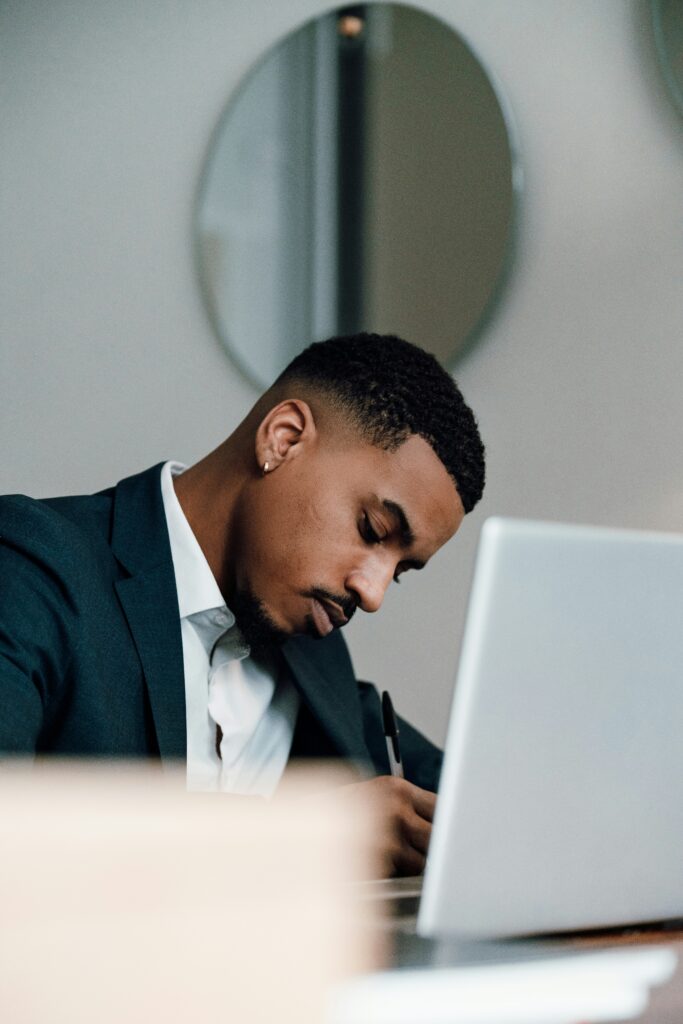 Young man seated at a desk in front of a laptop working